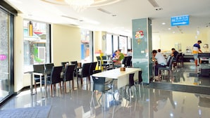 Un espace de restauration moderne, avec des tables et des chaises, un lustre et un panneau indiquant la direction de l’ascenseur.