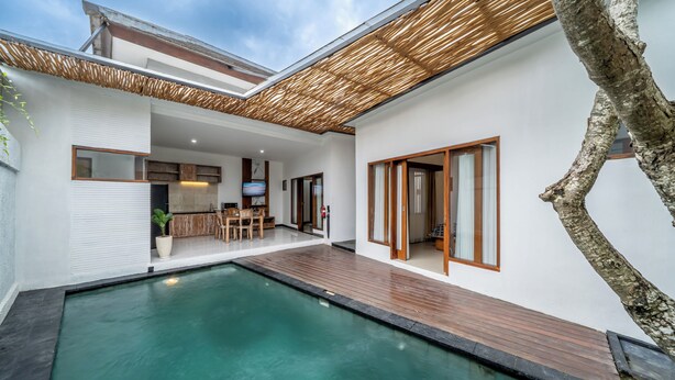A modern house with a swimming pool, wooden deck, and a covered outdoor area. - The Dewi Pererenan Villa and Suite (Canggu)