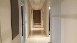 A modern, well-lit hallway with a glossy floor, leading to a door at the end. - iHome Residence (Jakarta)