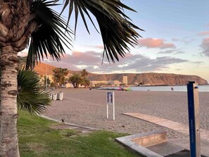 A beach with palm trees, a boardwalk, and a sign indicating 'Playa de Los Cristianos'. - Estudio Gavota (Arona)