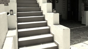 Una escalera conduce a la entrada de un edificio con un muro de piedra y un farol en el rellano.