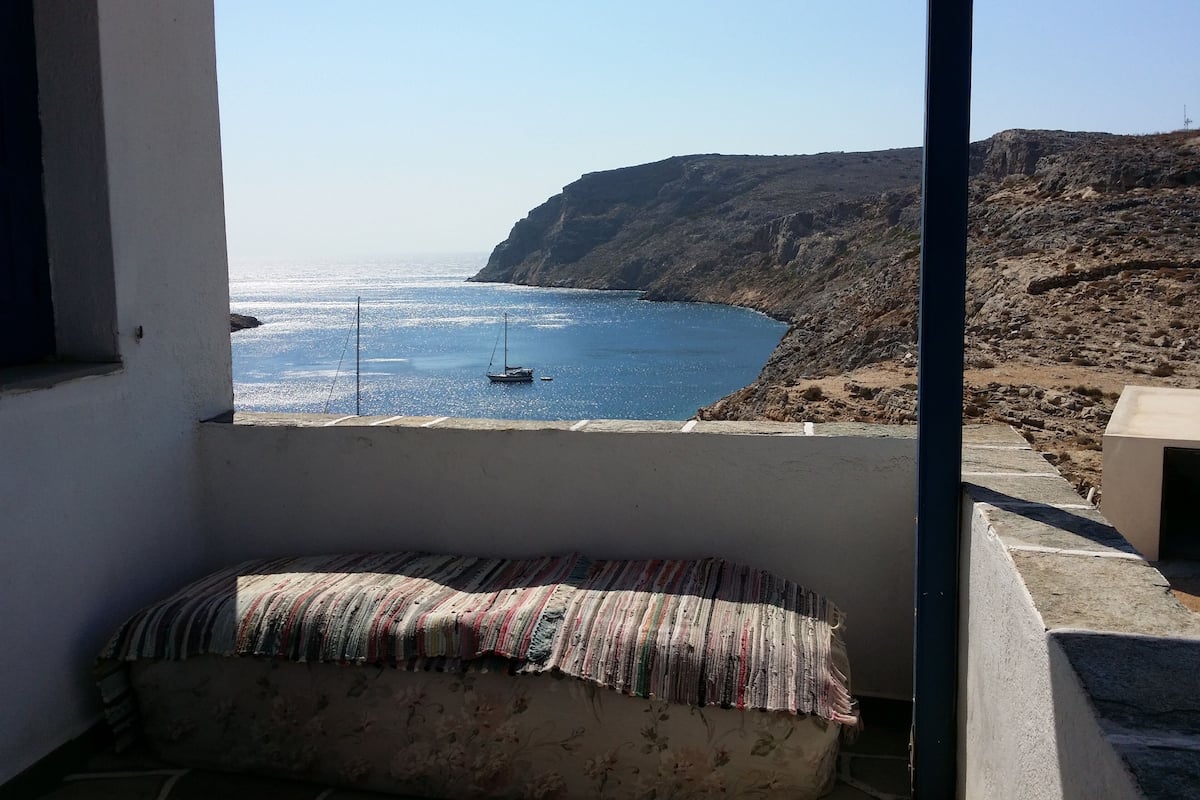 Un balcon avec vue sur la mer, un bateau et un paysage rocheux.