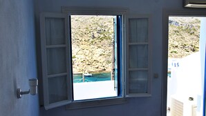 Una habitación con ventana que da a un paisaje rocoso y una masa de agua.