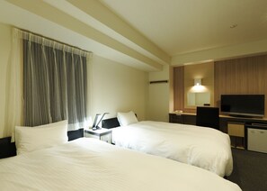 Habitación de hotel con dos camas, un escritorio, una televisión de pantalla plana, un espejo y una ventana con cortinas.