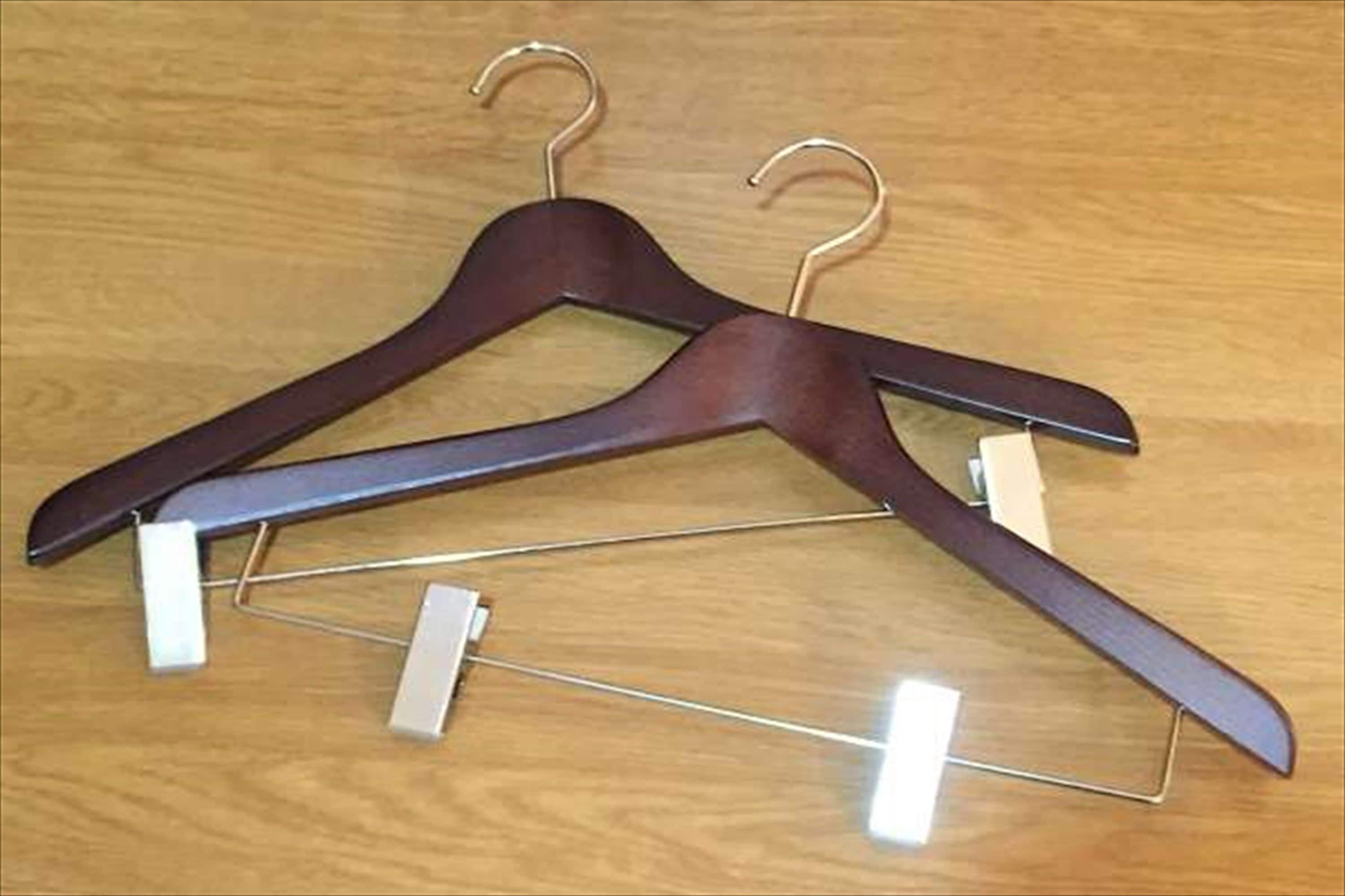 Zwei Holzkleiderbügel mit Metallbügeln auf einer Holzunterlage.