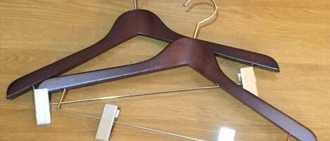 Zwei Holzkleiderbügel mit Metallbügeln auf einer Holzunterlage.