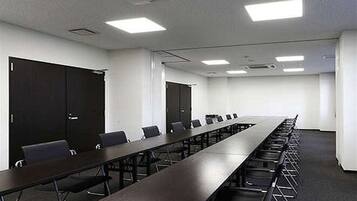 A conference room with a long table, chairs, and dark wooden doors.