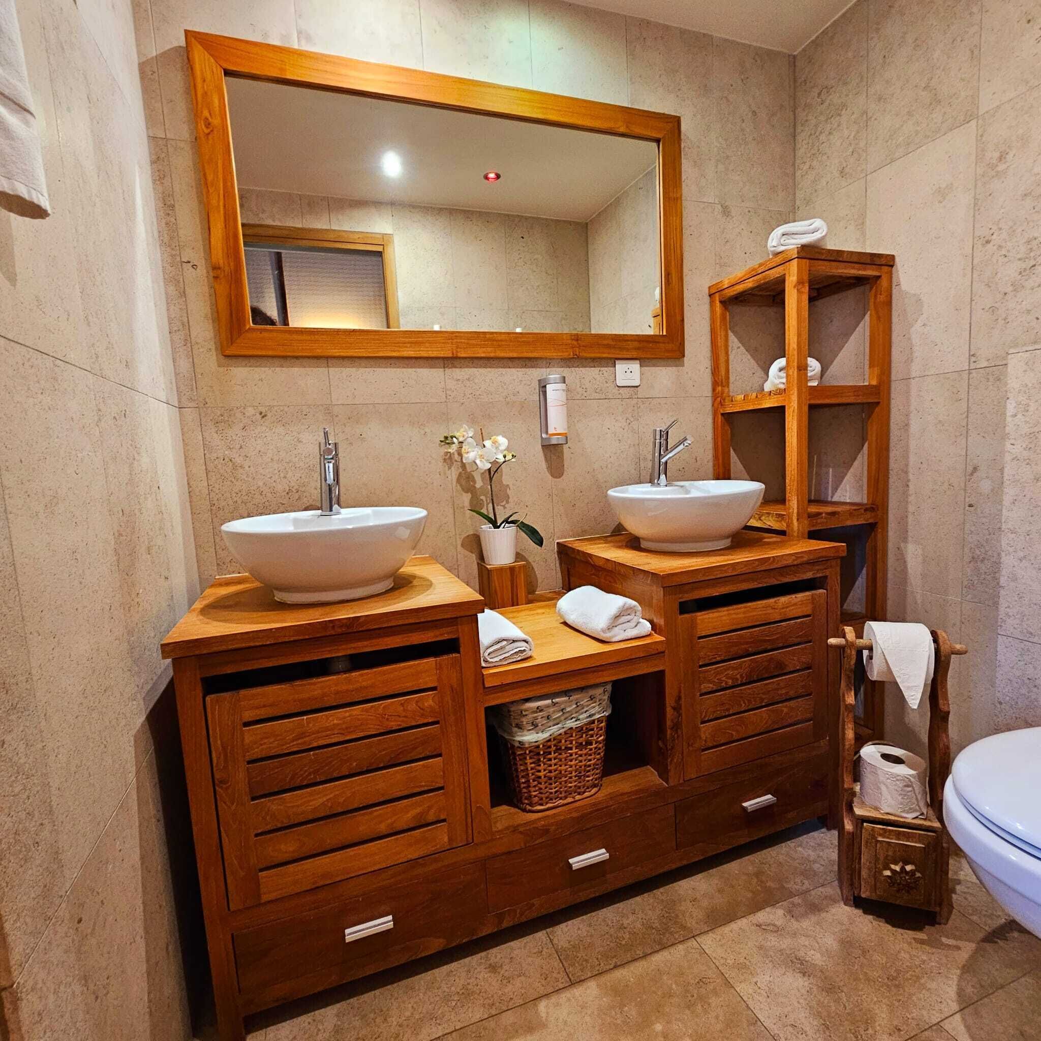 A bathroom with two sinks, a mirror, and wooden cabinets.