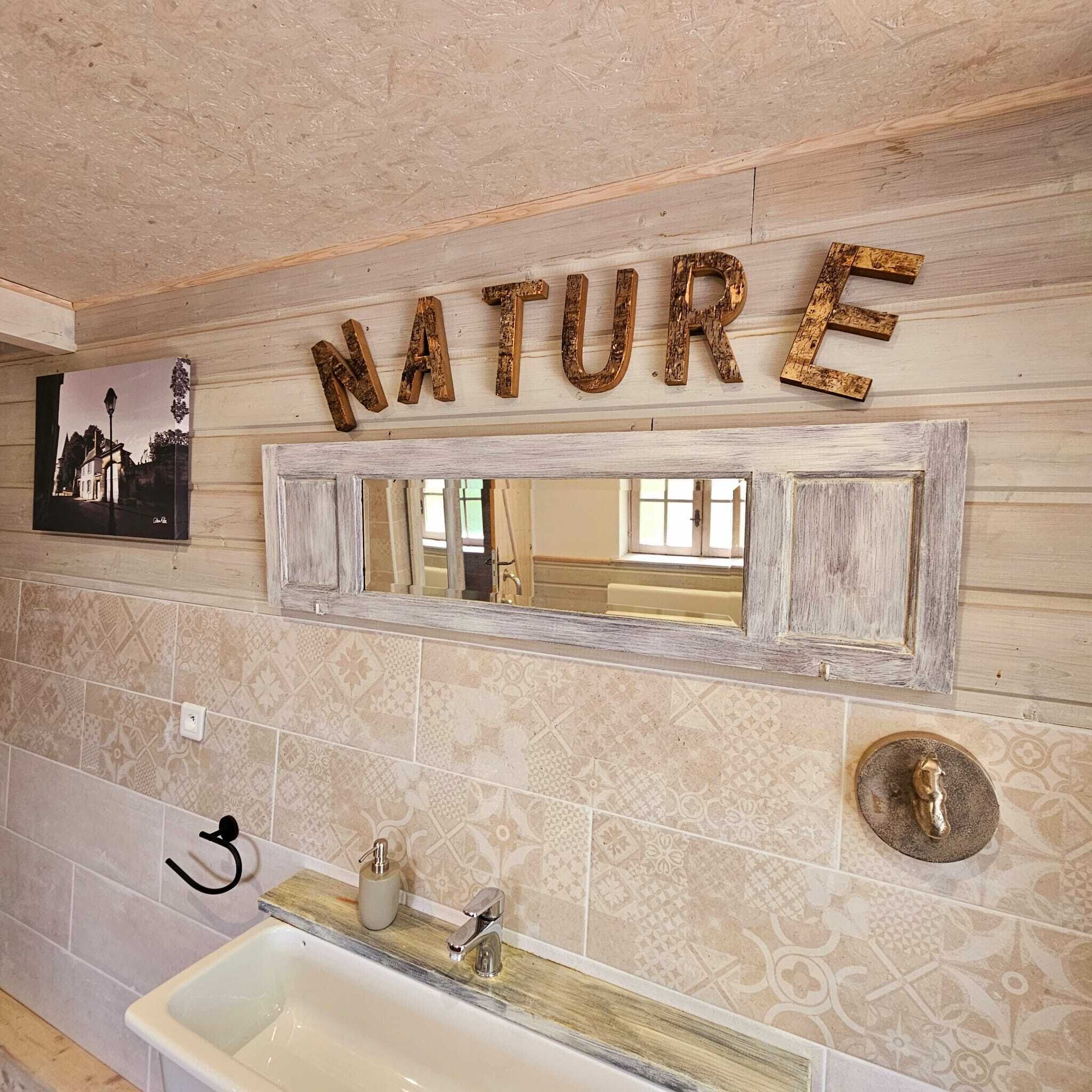 Ein Badezimmer mit Waschbecken, Spiegel und einem an der Wand befestigten Schild mit der Aufschrift 'NATURE'.