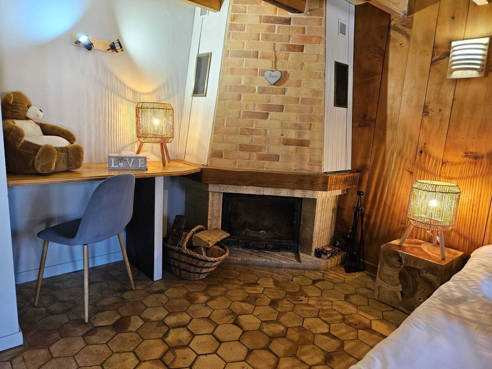 Een knus ingerichte kamer met een bakstenen openhaard, een bureau met stoel en een bed.