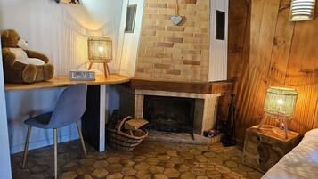 Een knus ingerichte kamer met een bakstenen openhaard, een bureau met stoel en een bed.