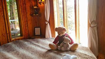 Une chambre confortable avec un grand lit, un ours en peluche et une fenêtre avec des rideaux.