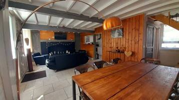 Amplia sala de estar con una mesa de comedor de madera, un sofá y una cocina al fondo.