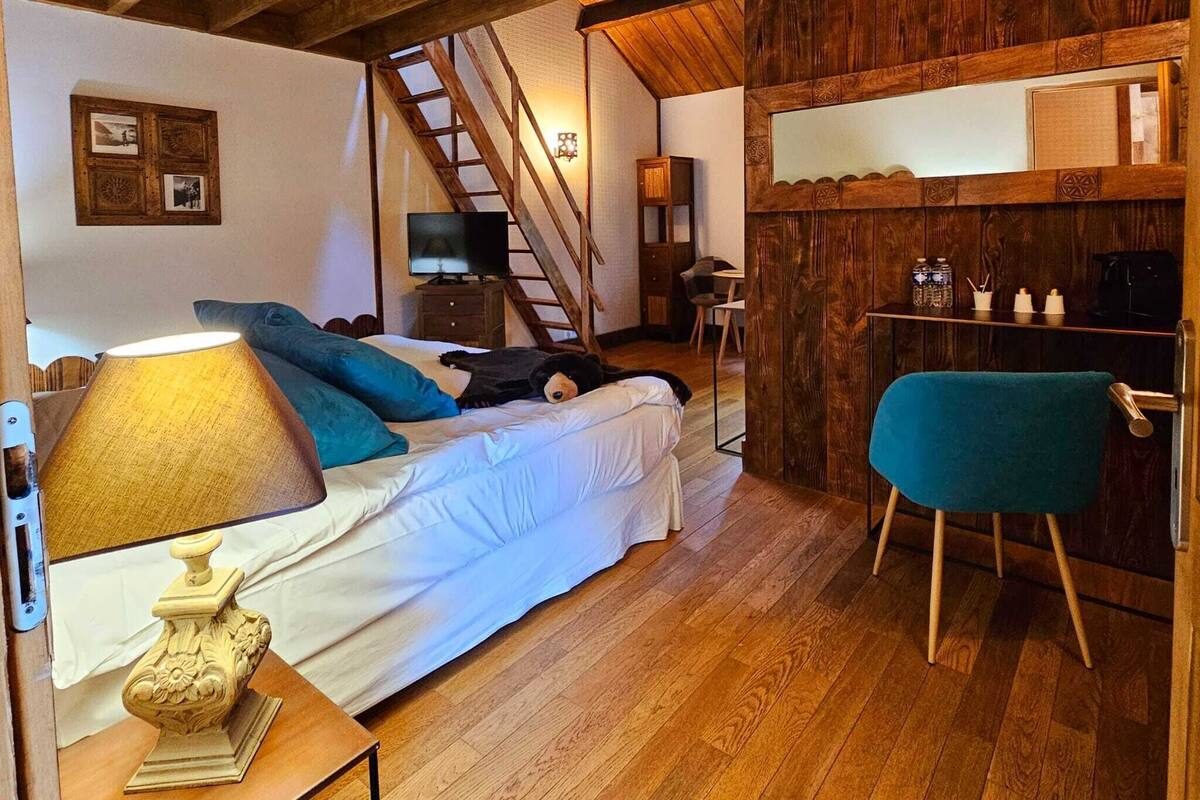 Een gezellige kamer met een bed, een bureau, een stoel, een lamp en een trap.