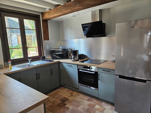 Una cocina moderna con gabinetes grises, un refrigerador de acero inoxidable, un microondas, una cafetera y un horno empotrado.