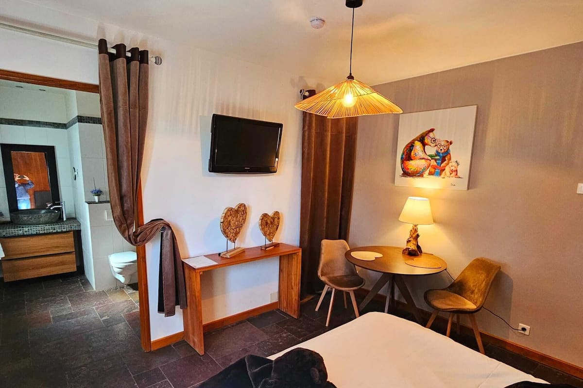 Een hotelkamer met een bed, een bureau met stoel, een televisie en een zithoek met tafel en stoelen.