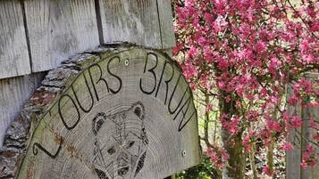 Ein hölzernes Schild mit der Aufschrift 'L'OURS BRUN' an einem Holzpfosten befestigt.