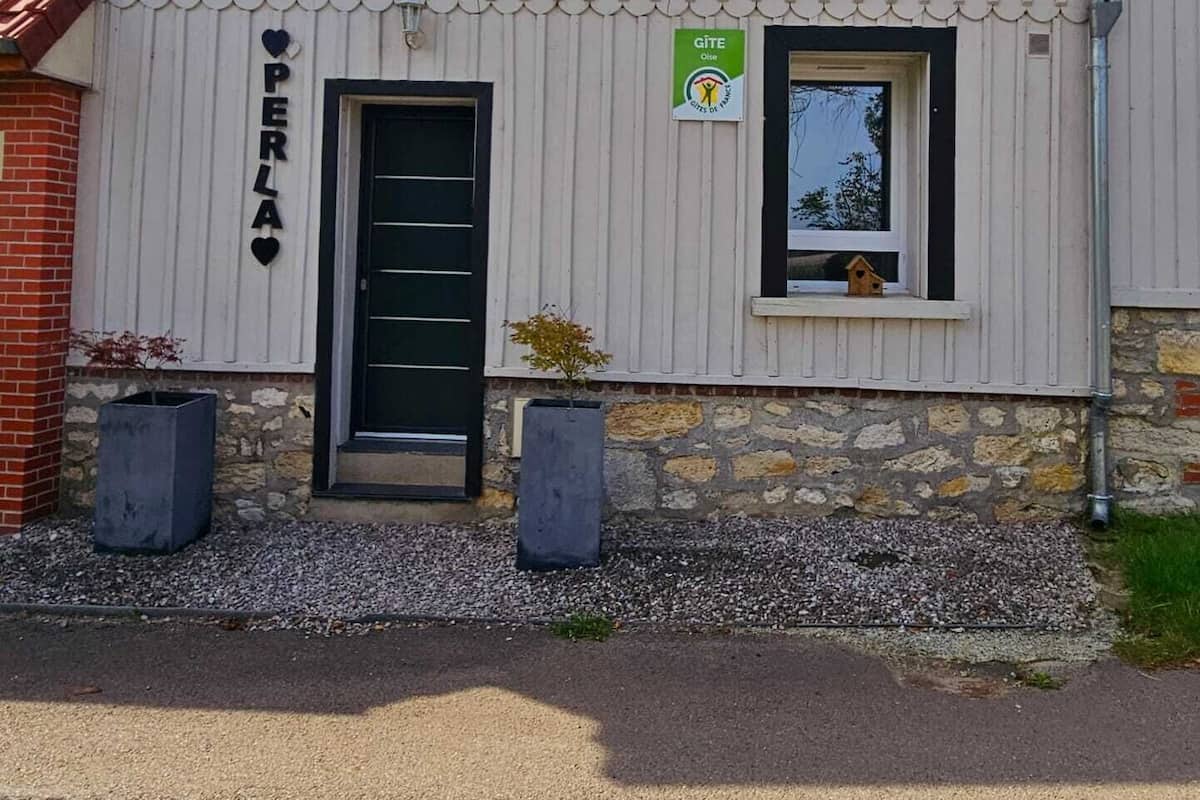 Een gebouw met een witte gevel, een zwarte deur en een klein raam met een vogelhuisje.