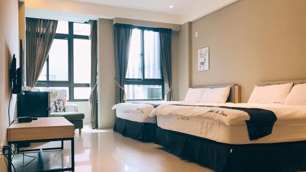 A hotel room with two beds, a desk, a TV, and large windows with curtains. - Cat Nap (Luodong)