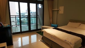A hotel room with a bed, a small table, a chair, and a view of the city through large windows. - Cat Nap (Luodong)