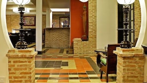 A lobby with a checkered floor, a statue, and a brick wall. - Villa Silk Road Hotel (Phnom Penh)