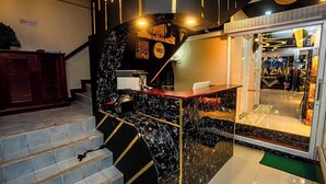 A reception area with a marble counter, a staircase, and a glass door leading to a restaurant. - Break Point Patong Hotel (Patong)