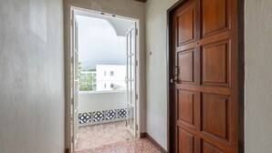 A hallway with a wooden door and a glass door leading to a balcony. - Break Point Patong Hotel (Patong)