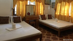 Une chambre d’hôtel avec deux lits, une commode en bois, un miroir et des rideaux.