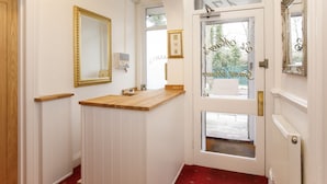 A hallway with white walls, wooden trim, and a red carpet. There are framed mirrors and a door with a glass panel. - St Mary's Guest House  (York)