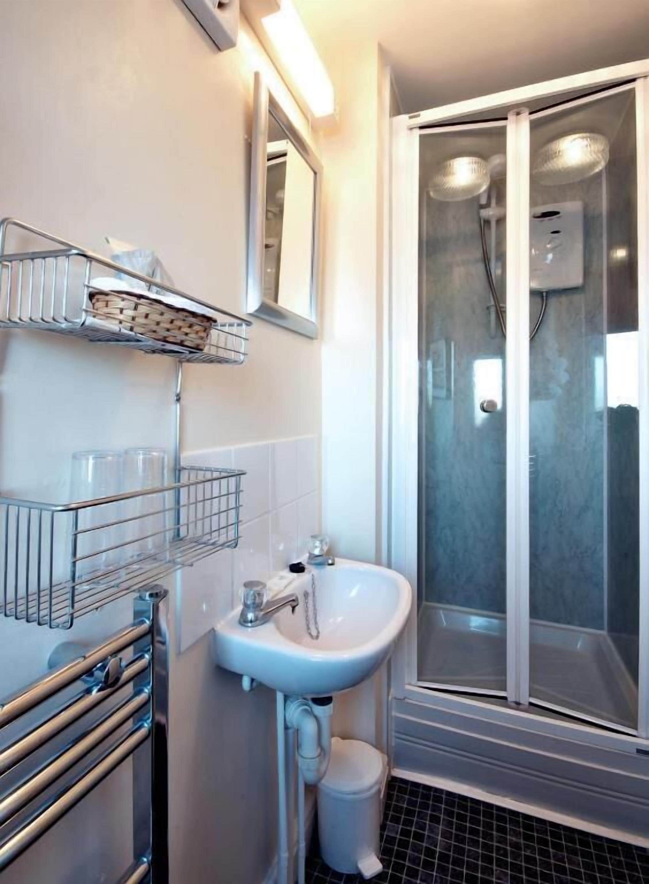 A bathroom with a sink, mirror, and shower.