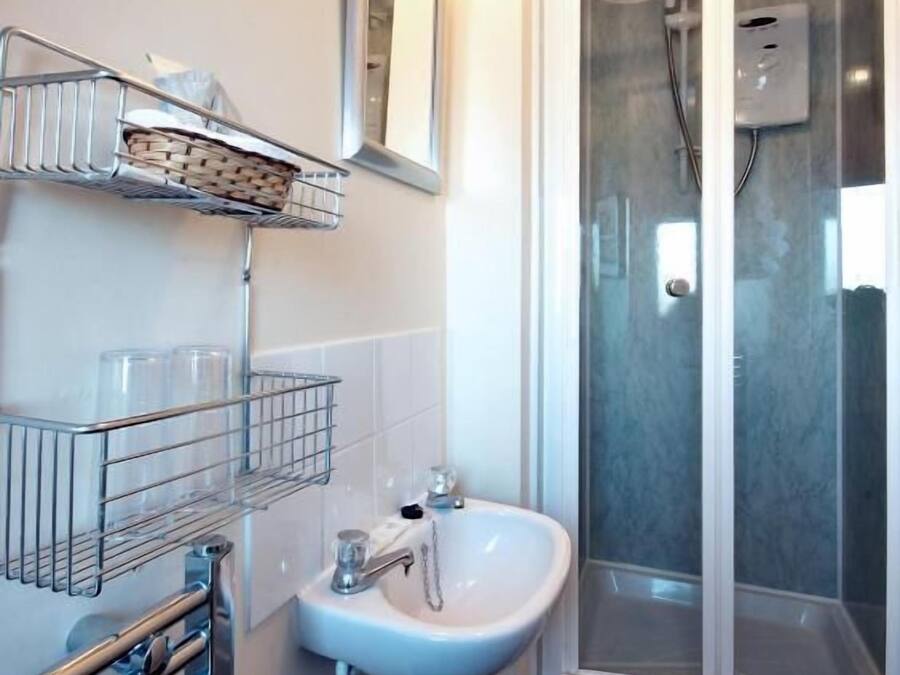 A bathroom with a sink, mirror, and shower.