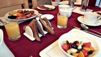 A breakfast setting with toast, fruit, and juice on a table.