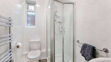 A bathroom with a glass-enclosed shower, a toilet, and a towel rack.