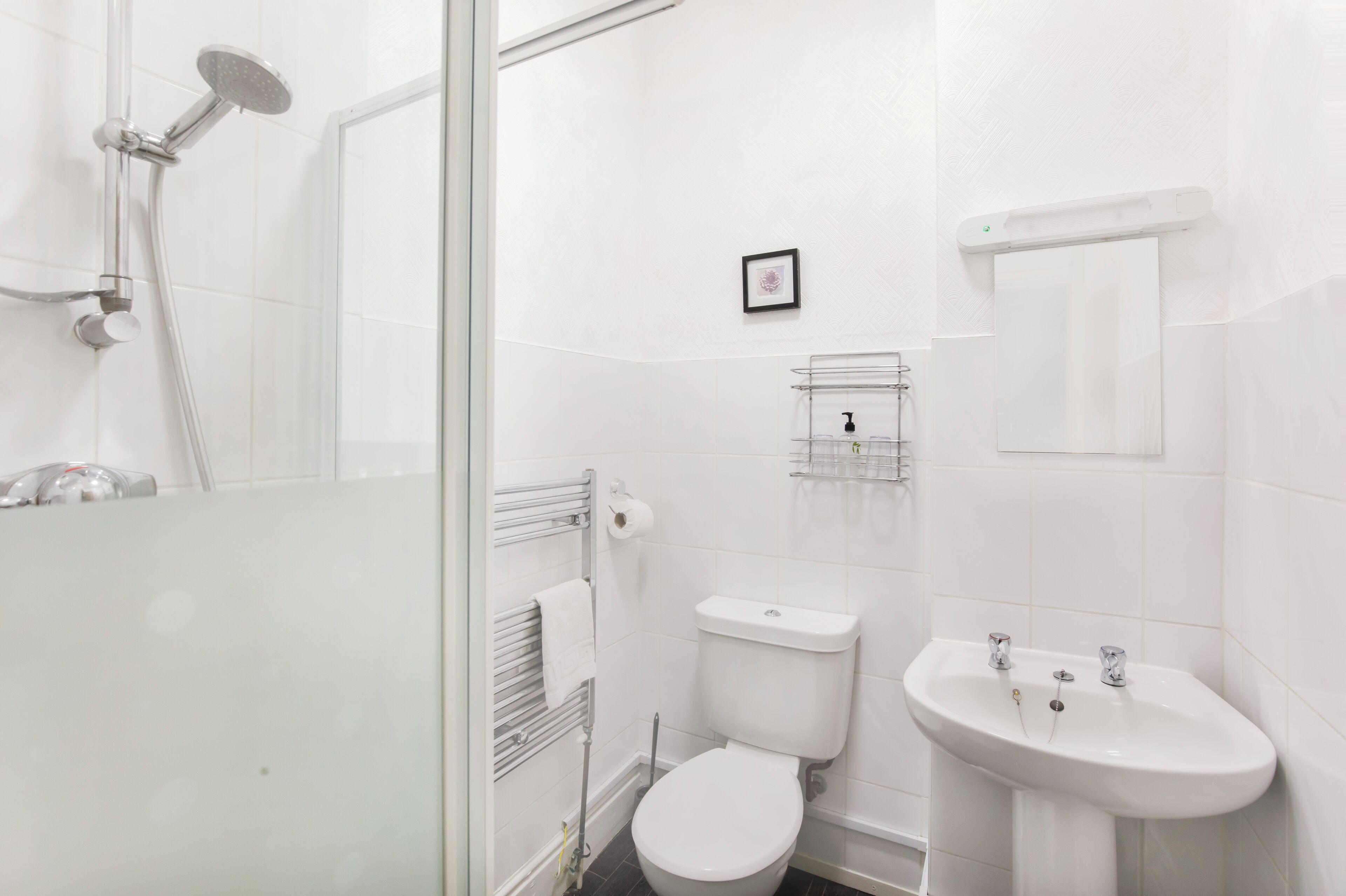 Un baño moderno con cabina de ducha de vidrio, inodoro y lavamanos.