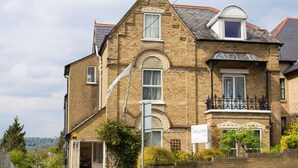 A two-story brick building with a balcony, a garage entrance, and a small window. - Abbey Lodge Hotel (High Wycombe)