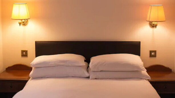 A hotel room with a bed, two bedside tables, and two wall-mounted lamps. - Abbey Lodge Hotel (High Wycombe)