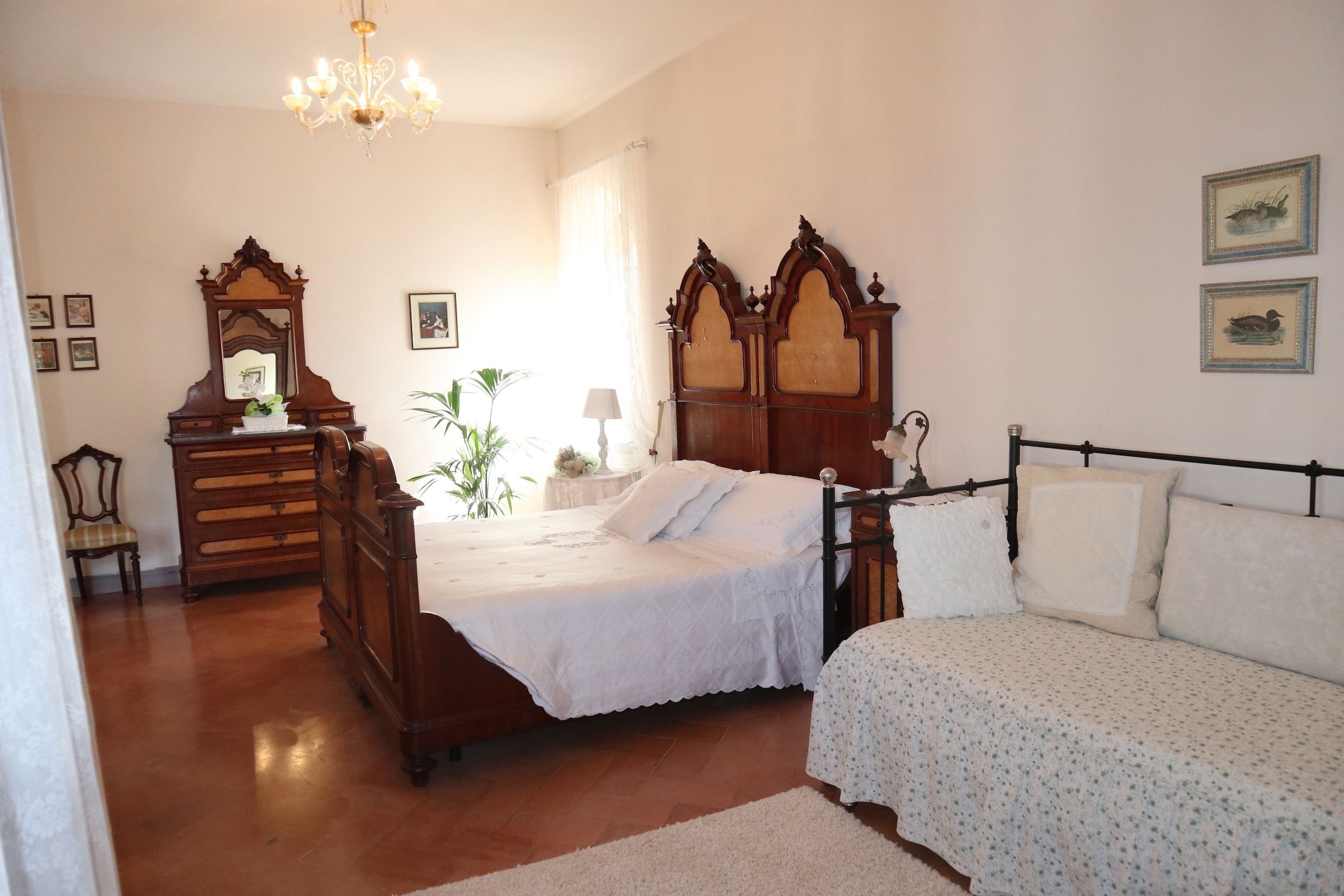 A bedroom with a wooden bed, a nightstand, a dresser, and a chandelier.