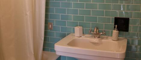 A bathroom with a white sink, a mirror with a floral frame, and a shower curtain.