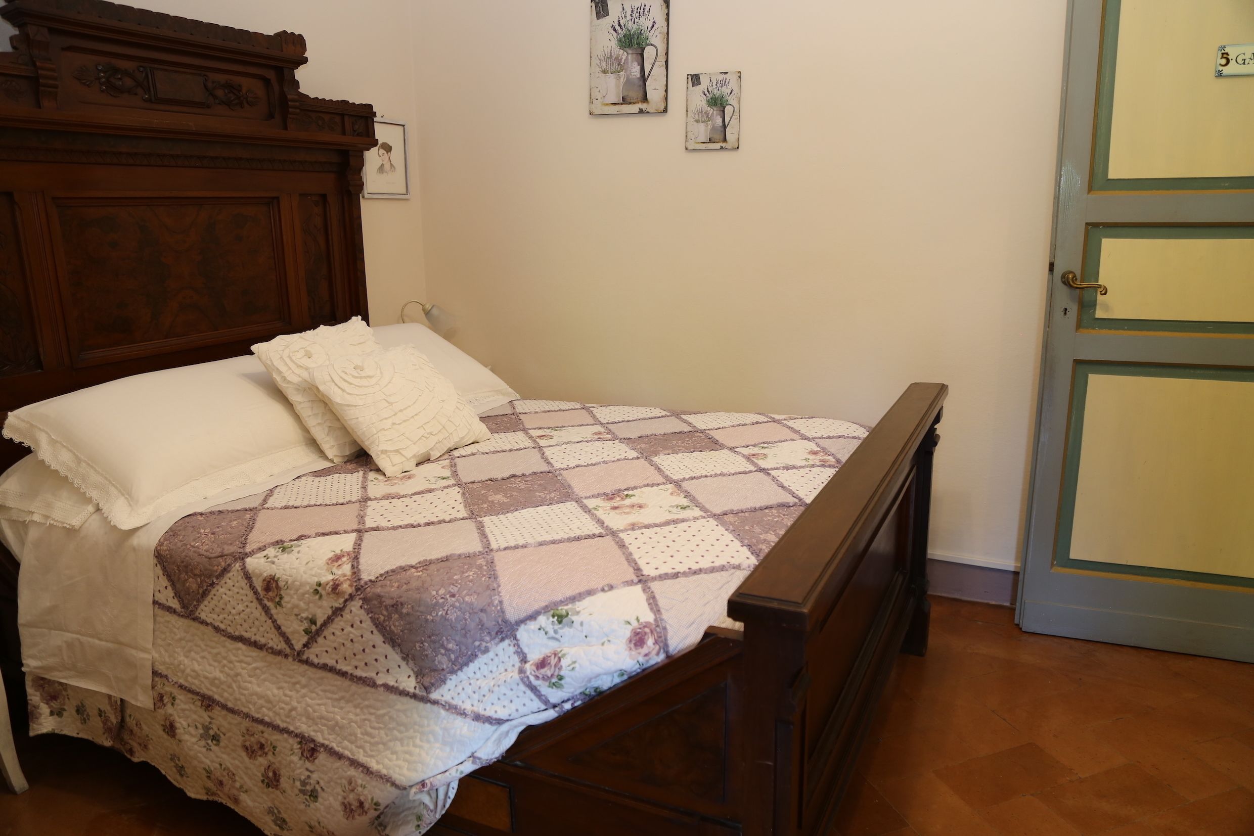 Un letto ben rifatto con una coperta a fiori e una testiera in legno.