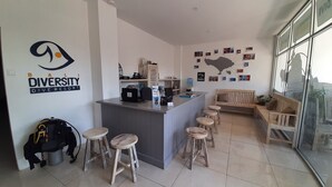 Un área de recepción con mostrador, taburetes de bar, un banco de madera y una pared con fotografías.