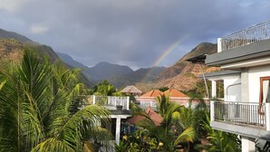 Un barrio residencial con casas, montañas al fondo y un arcoíris visible.