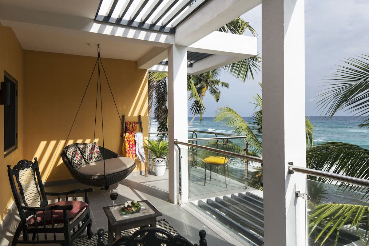 A balcony with a wicker chair, a dining table, and a potted plant.