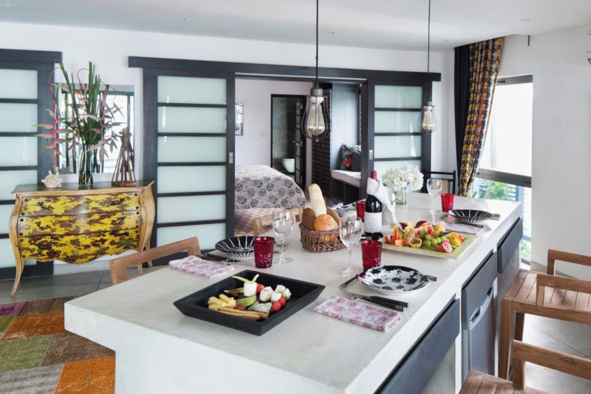A modern kitchen with a central island, dining table, and chairs.