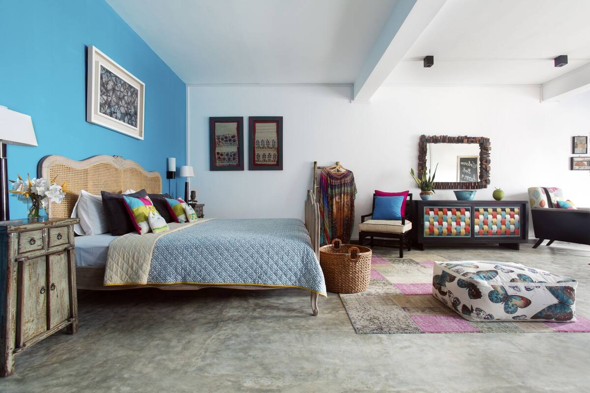 A bedroom with a bed, a dresser, a chair, a sofa, and a mirror.