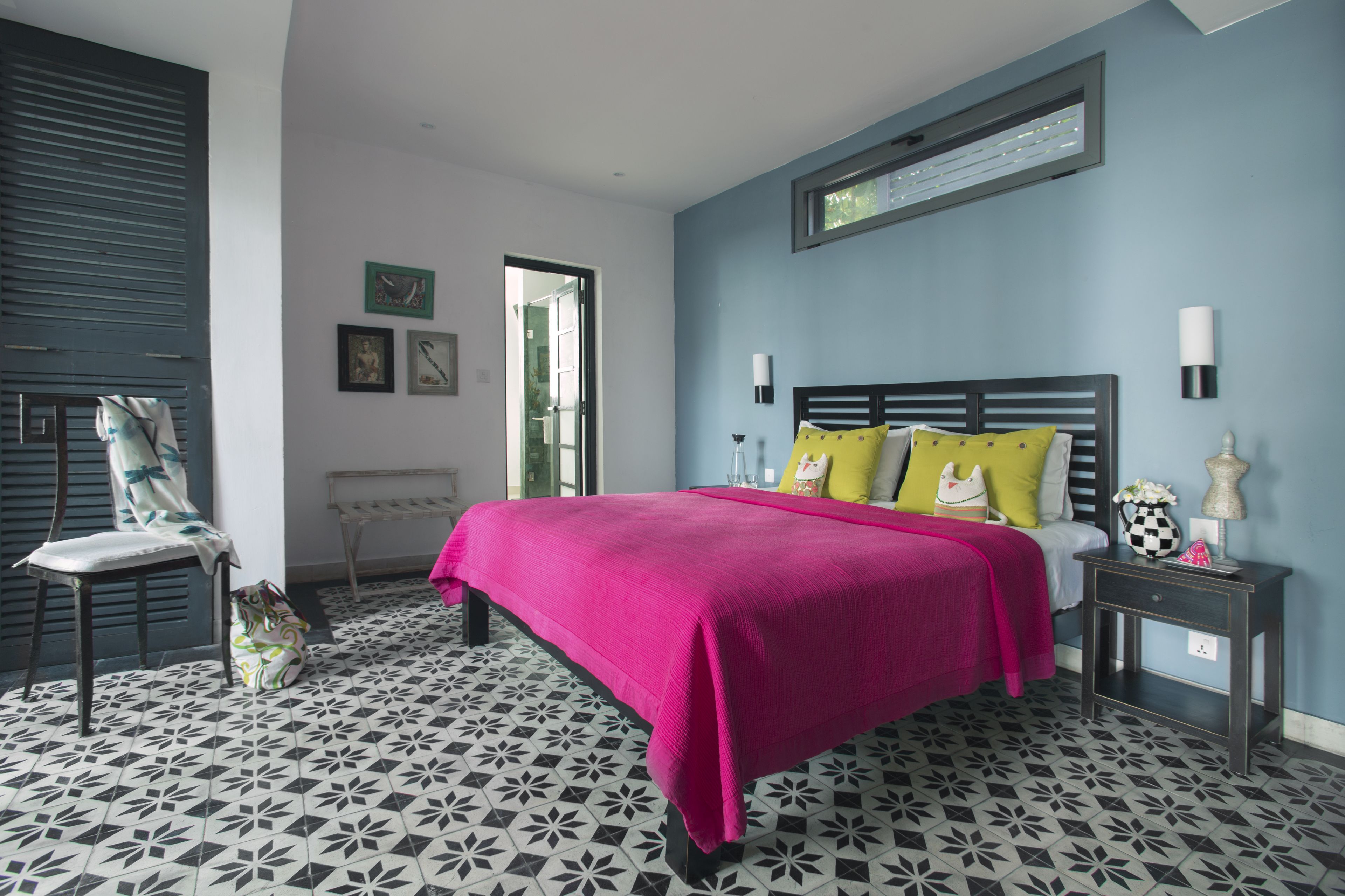 A bedroom with a bed, a chair, a bedside table, and a window.