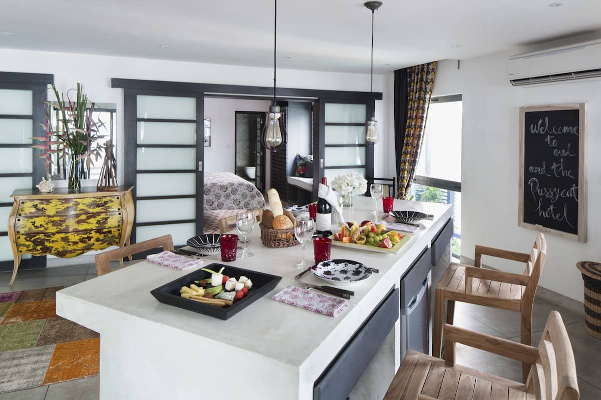 A modern kitchen with a central island, wooden chairs, and a chalkboard sign.