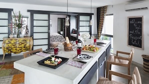 Une cuisine moderne avec un îlot central, des chaises en bois et un panneau d’affichage en forme d’ardoise.