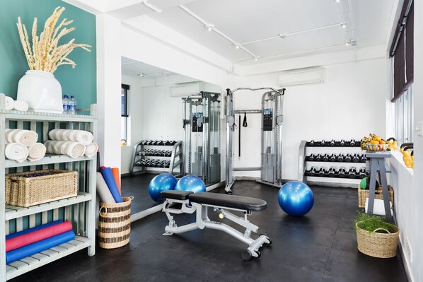 Un gimnasio con equipamiento de ejercicio, toallas y pesas.