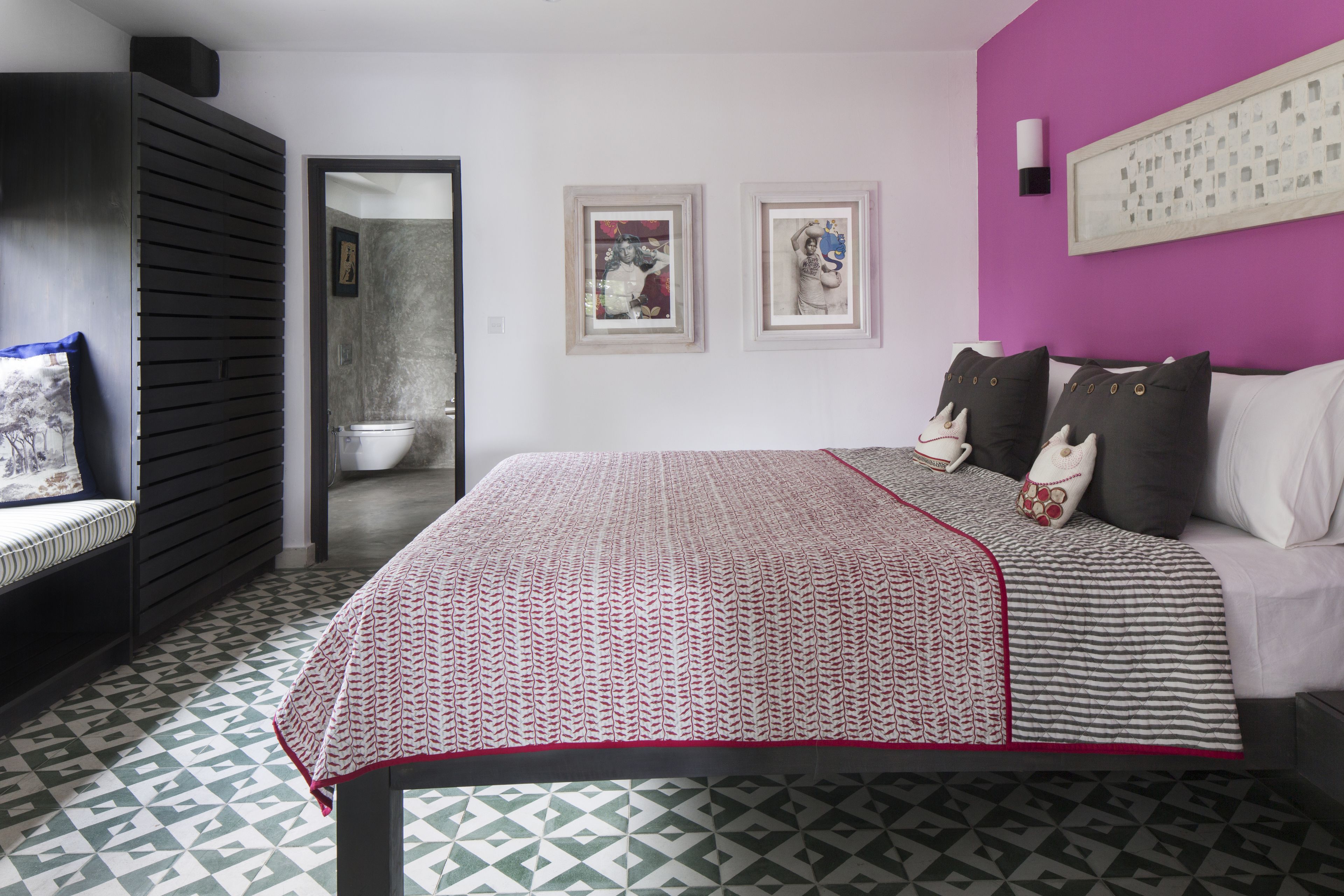 Une chambre à coucher avec une couvre-lit à motifs, un canapé et un téléviseur fixé au mur.