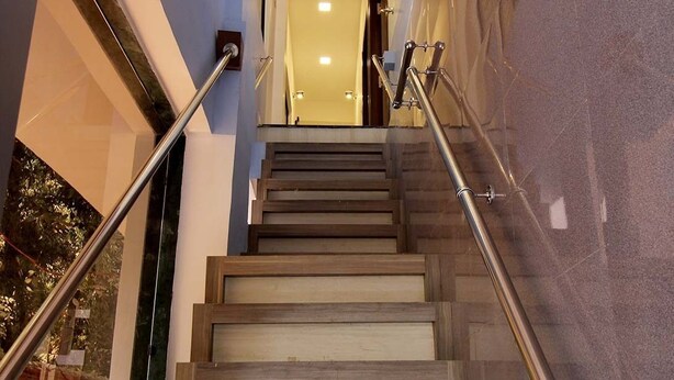 A staircase with wooden steps and metal handrails, leading to an interior space with a light-colored wall and a door at the top. - Hotel Golden Residency (Mumbai)